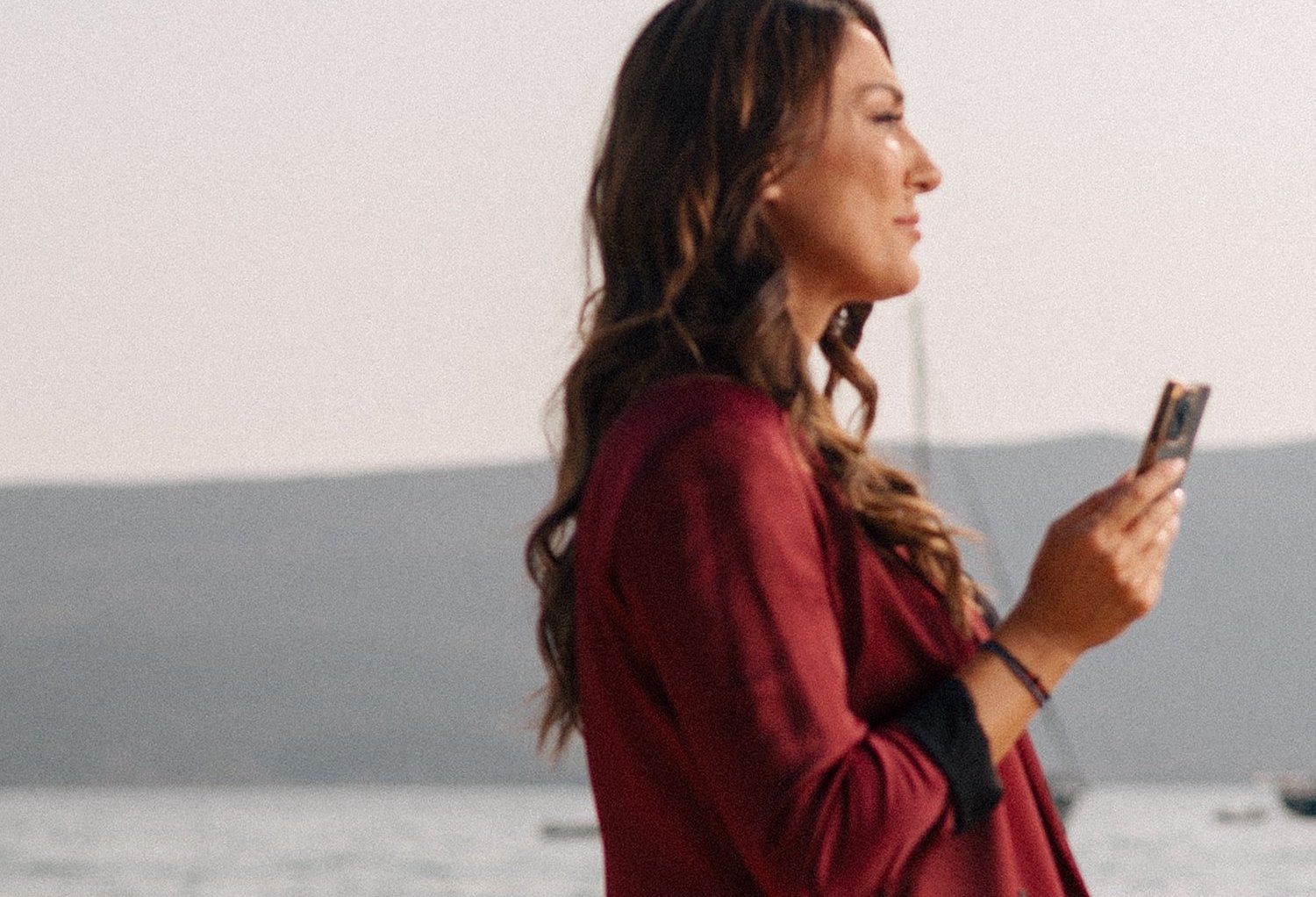 Jelena Bojić with a phone at the Tivat waterfront, social media planning